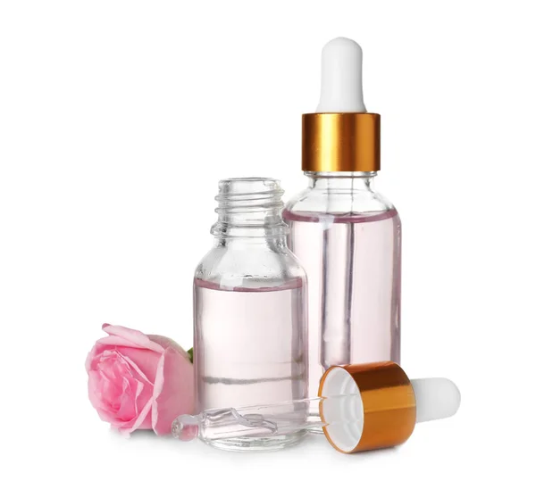 Botellas con aceite esencial de rosa y flor sobre fondo blanco — Foto de Stock