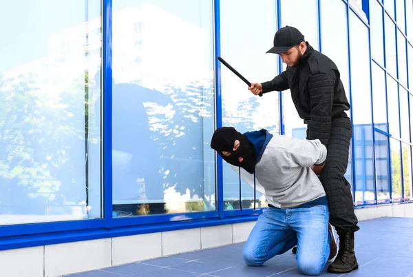 Polizist mit Schlagstock nimmt maskierten Verbrecher im Freien fest — Stockfoto