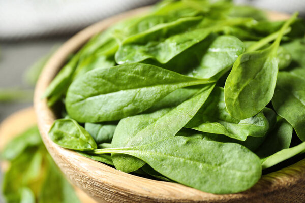 Fresh green healthy spinach in wooden bowl, closeup