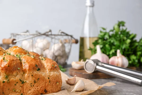 Pedaços de pão com alho e ervas na mesa cinza contra fundo claro — Fotografia de Stock