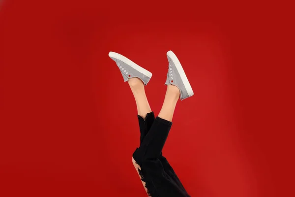 Kırmızı arka planda şık spor ayakkabı kadın — Stok fotoğraf