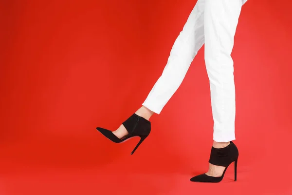 Kvinna i eleganta skor på röd bakgrund — Stockfoto