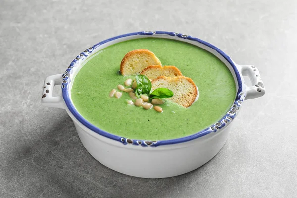 Bowl of healthy green soup with fresh spinach on light table