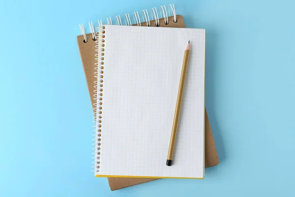 Notizbücher mit Bleistift auf hellblauem Hintergrund, Draufsicht — Stockfoto