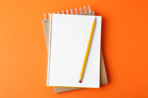Quaderni con matita su sfondo arancione, vista dall'alto — Foto Stock