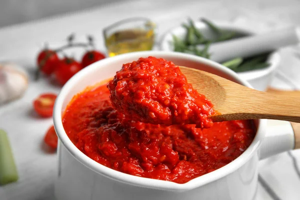 Colher e panela com molho de tomate delicioso, vista de perto — Fotografia de Stock