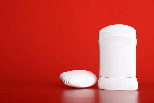 Pegue el desodorante sobre la mesa sobre el fondo rojo. Espacio para el diseño — Foto de Stock