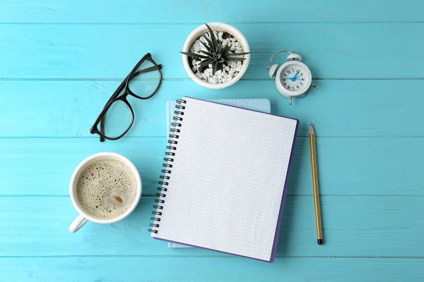 Composição de leigos plana com papelaria de escritório e xícara de café em mesa de madeira azul clara. Espaço para texto — Fotografia de Stock