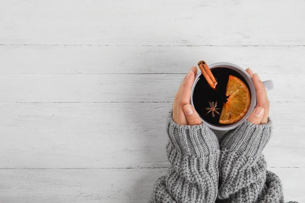 Femme tenant une tasse de vin chaud chaud chaud à la table en bois blanc, vue du dessus avec espace pour le texte. Boisson d'hiver — Photo