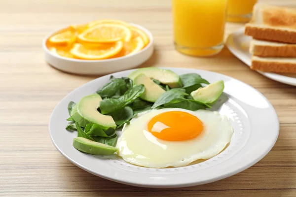 Тарелка яичницы с авокадо и шпинатом на деревянном столе. Здоровый завтрак — стоковое фото