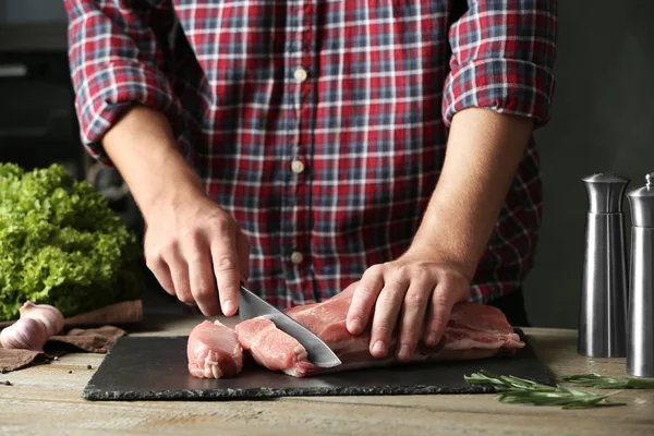 Homem cortando carne crua fresca na mesa de madeira, close-up — Fotografia de Stock