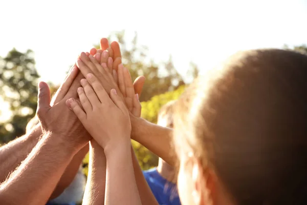 Groep vrijwilligers die de handen in de buitenlucht op zonnige dag samenvoegen — Stockfoto