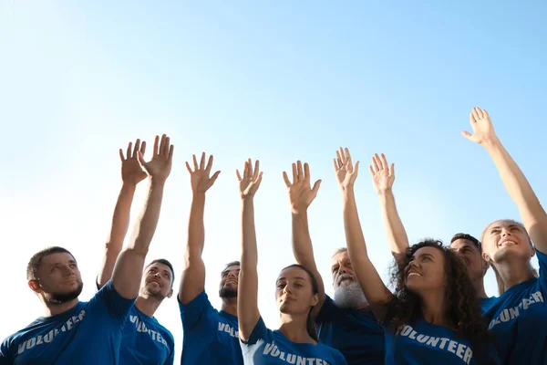 Grupo de voluntarios levantando las manos al aire libre en un día soleado — Foto de Stock