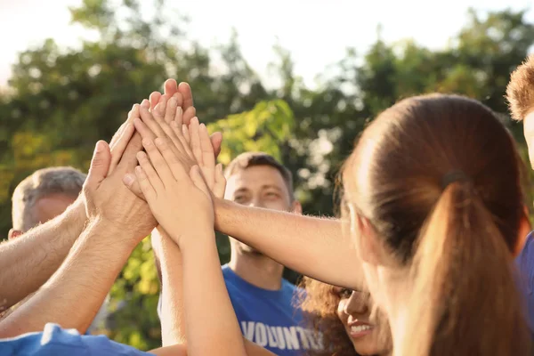 Grupa wolontariuszy łączących ręce razem na zewnątrz w słoneczny dzień — Zdjęcie stockowe