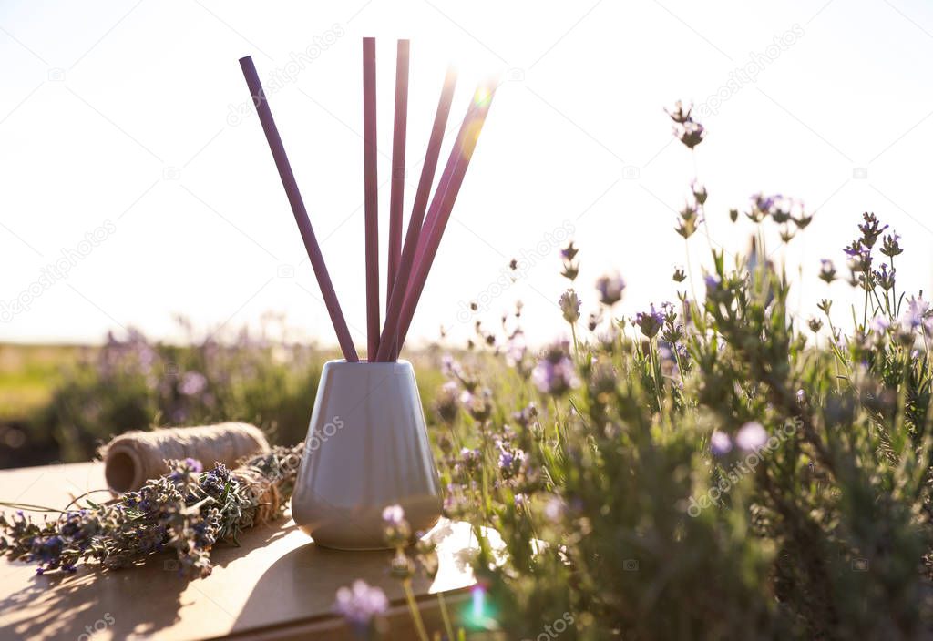 Reed air freshener on wooden table in blooming lavender field