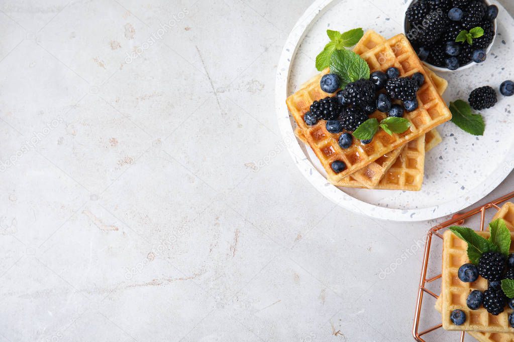 Delicious waffles with fresh berries served on grey table, top view. Space for text