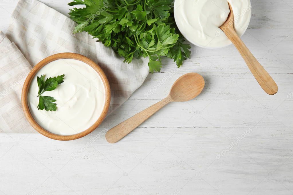 Flat lay composition with sour cream and parsley on white wooden table. Space for text