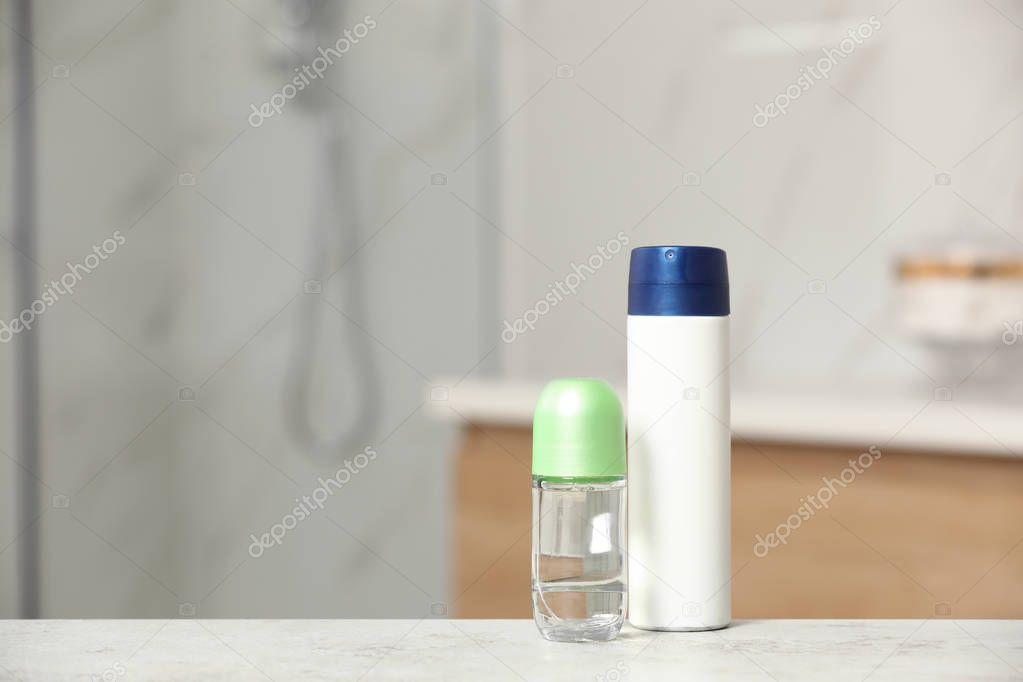 Different deodorants on table in bathroom, space for text