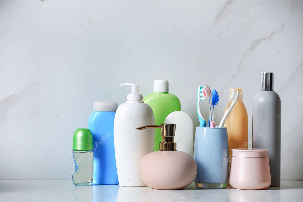 Roll-on deodorant and different toiletry on marble table near light wall
