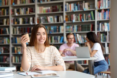Kütüphanede masada içki içen genç bir kadın. Metin için alan