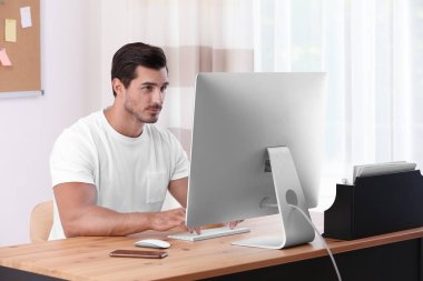 Ofiste masada bilgisayar ile çalışan yakışıklı genç adam