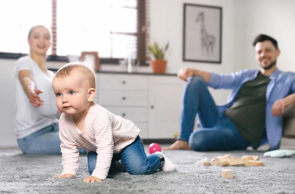 Parents watching their baby crawl on floor at home — Stock Photo, Image