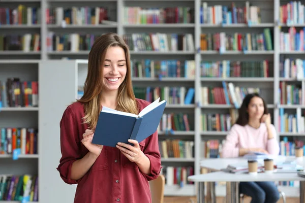 Młoda ładna kobieta czytanie książki w bibliotece. Miejsce na tekst — Zdjęcie stockowe