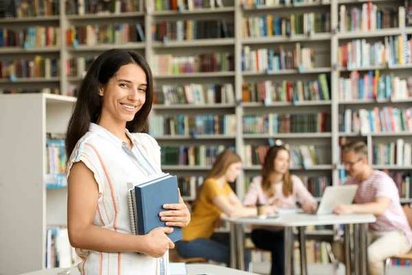 Счастливая молодая женщина с книгами в библиотеке. Пространство для текста — стоковое фото