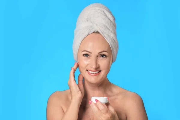 Portret van mooie rijpe vrouw met perfecte huid houden jar van crème op licht blauwe achtergrond — Stockfoto