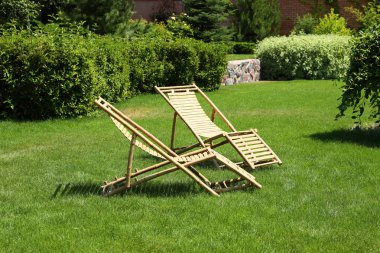 Güneşli günde güzel bahçede Ahşap şezlonglar