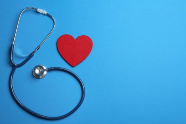 Stetoskop ve mavi arka plan üzerinde kırmızı kalp, düz metin için boşluk yatıyordu. Sağlık sigortası kavramı