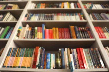 Kütüphanede kitap ile rafların bulanık görünümü, düşük açı
