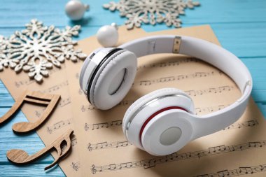 Mavi ahşap masa üzerinde Noel süslemeleri, kulaklık ve müzik levhalar, closeup