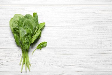 Beyaz ahşap masa üzerinde taze yeşil sağlıklı ıspanak, üst görünümü. Metin için alan