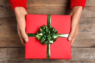 Ahşap masada Noel hediyesi tutan kadın, üst görünümü