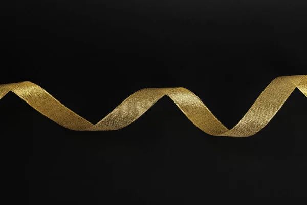 Elegant gold satin ribbon on black background