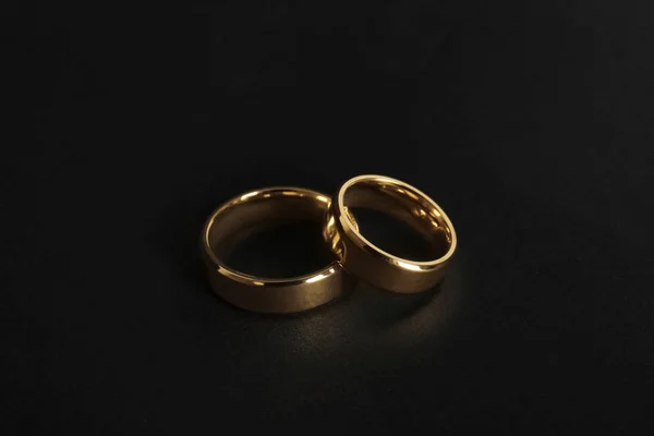 Hermosos anillos de boda de oro sobre fondo negro — Foto de Stock