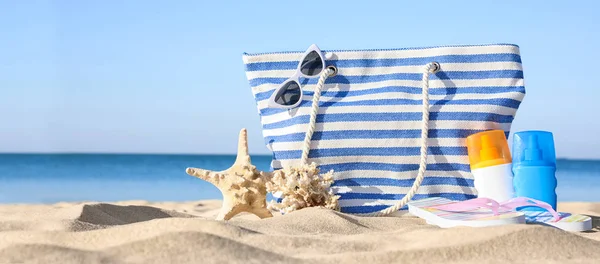 Set with stylish beach accessories on sand near sea — Stock Photo, Image