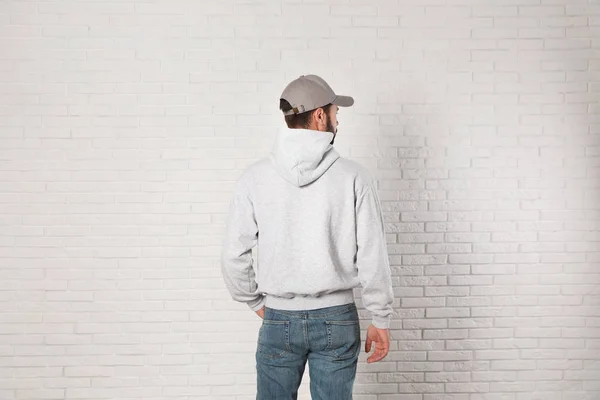 Молодой человек в свитере у кирпичной стены. Задумайтесь над дизайном — стоковое фото