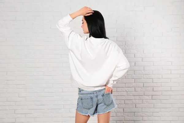 レンガの壁にセーターを着た若い女性デザインのモックアップ — ストック写真