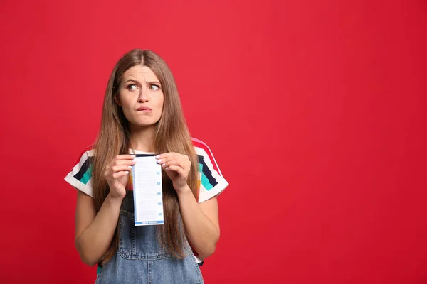 Portret van emotionele jonge vrouw met loterij ticket op rode achtergrond, ruimte voor tekst — Stockfoto