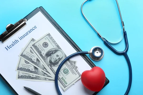 Плоская композиция с формой медицинского страхования, деньгами, сердцем и стетоскопом на синем фоне — стоковое фото