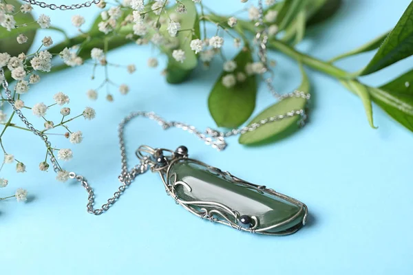 水色の背景にネフリットの宝石と花と美しい銀のネックレス — ストック写真