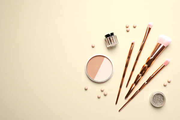 Flat lay composition with makeup brushes on beige background. Space for text