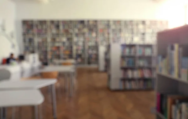 Vista borrosa del interior de la biblioteca con librerías y mesas —  Fotos de Stock