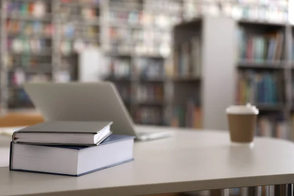 Книги, ноутбук і напої на столі в бібліотеці — стокове фото