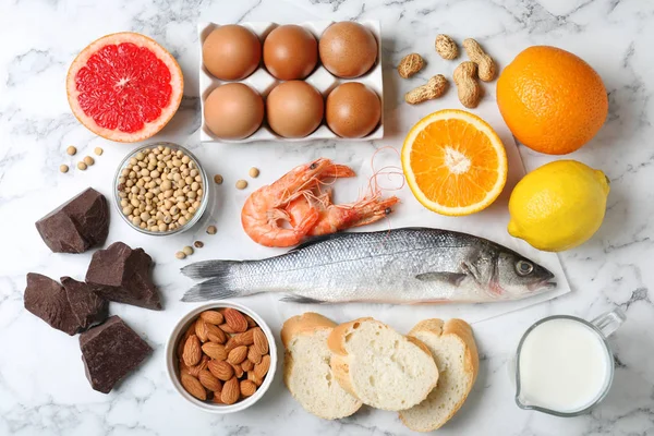 Flat lay composition of different products on white marble table. Food allergy concept — Stock Photo, Image