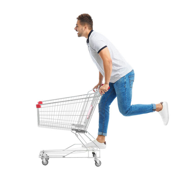 Young man with empty shopping cart on white background