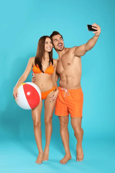 Joven pareja atractiva en ropa de playa con bola tomando selfie sobre fondo azul — Foto de Stock