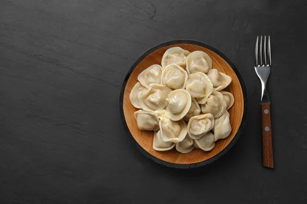 Smakelijke dumplings met boter op zwarte tafel, platte lag. Ruimte voor tekst — Stockfoto